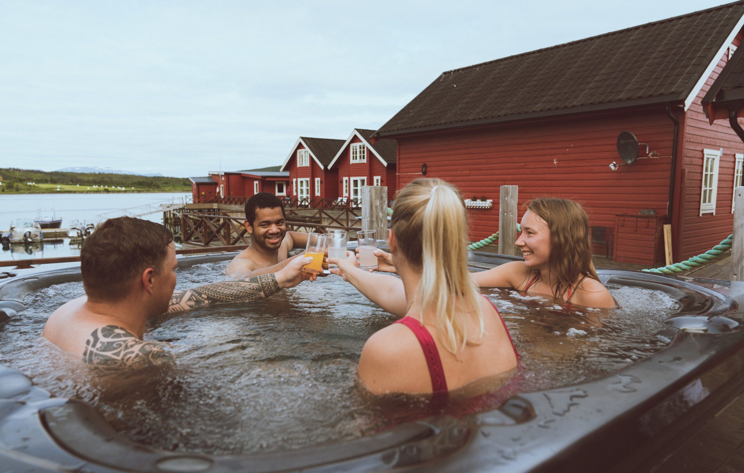 group of friends relaxing in jacuzzi with view of Lyngen Alps, Norway